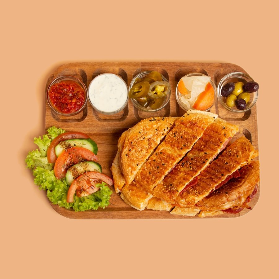 Getoastetes Sandwich in Scheiben mit Salat, Dips und Oliven auf einem Holzbrett